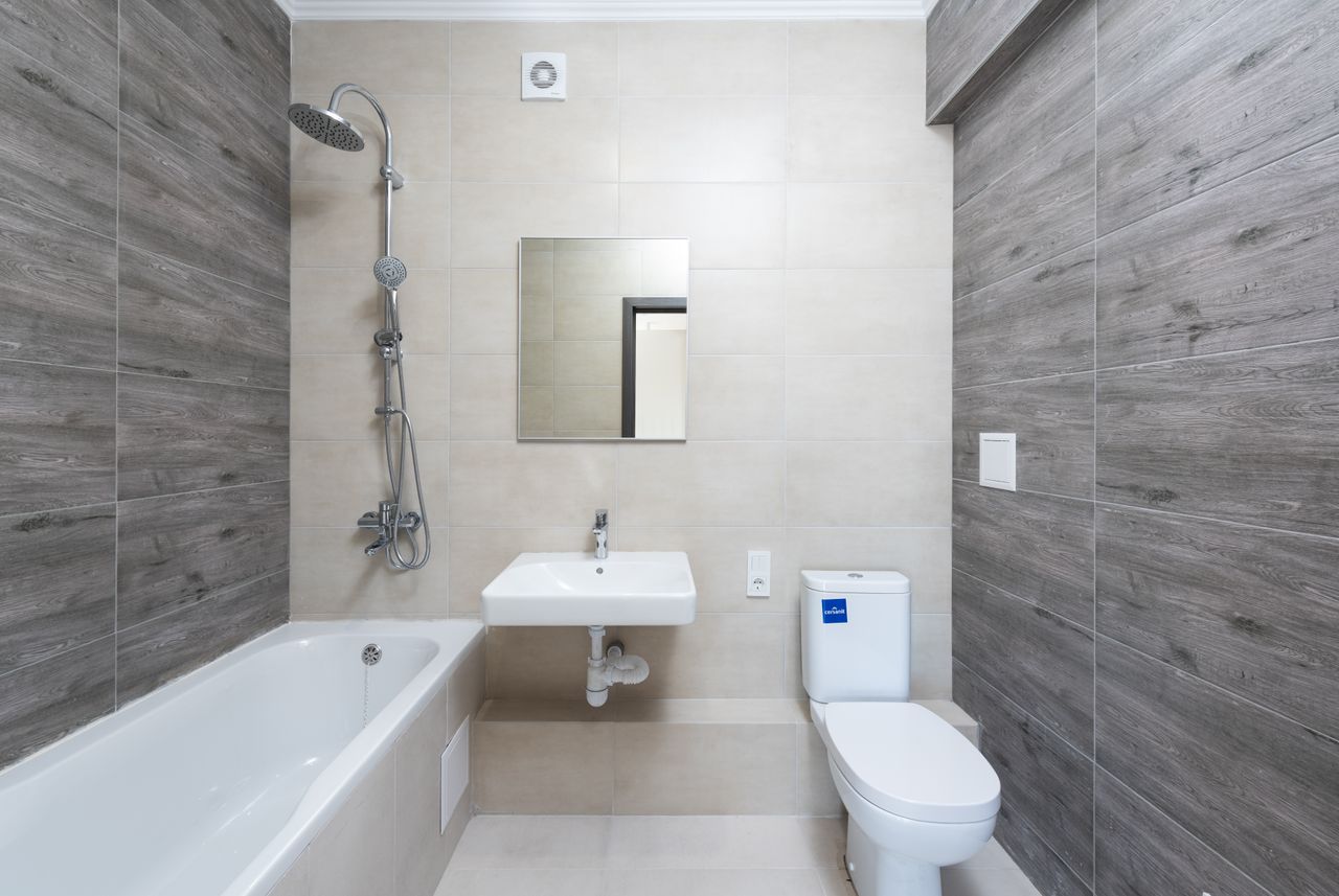 services-01 A contemporary bathroom features a bathtub, sink, and toilet with wood accents.